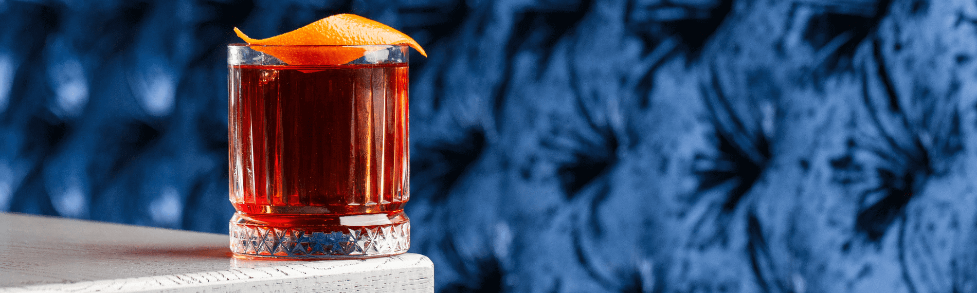 Cocktail with orange peel on table.
