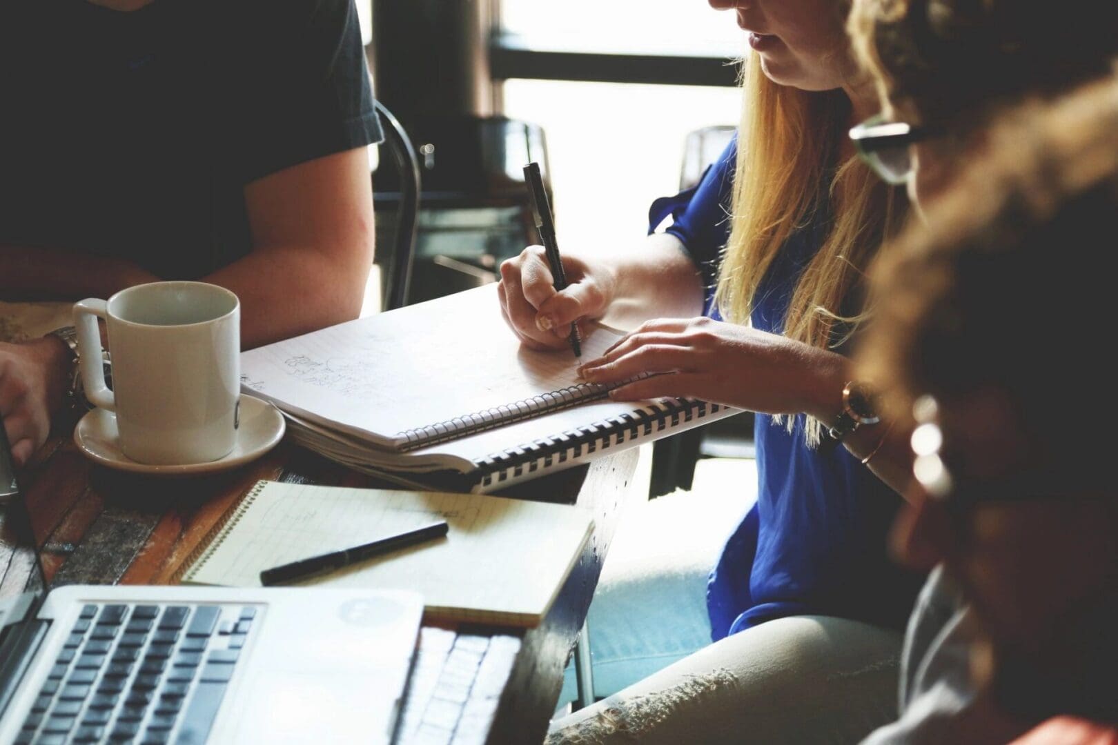 People collaborating at a table with notebooks.